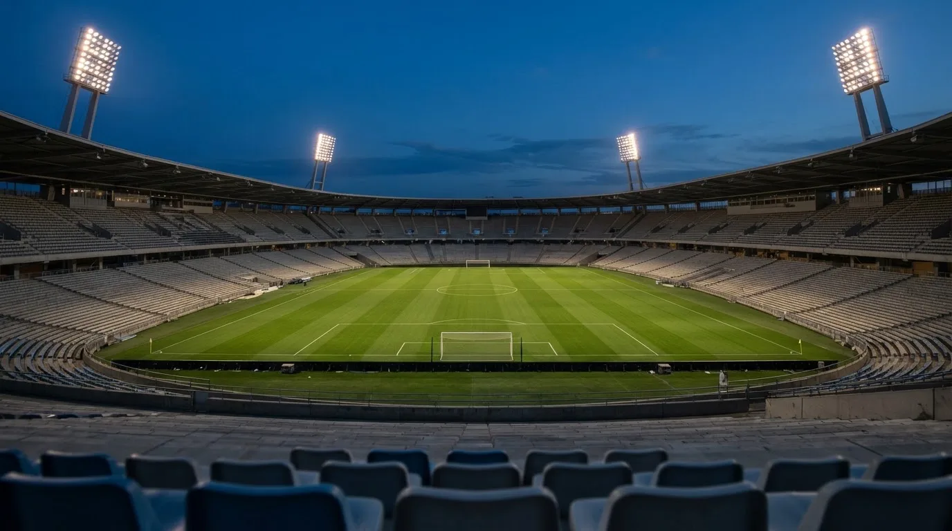 An empty football stadium with floodlight masts at dusk