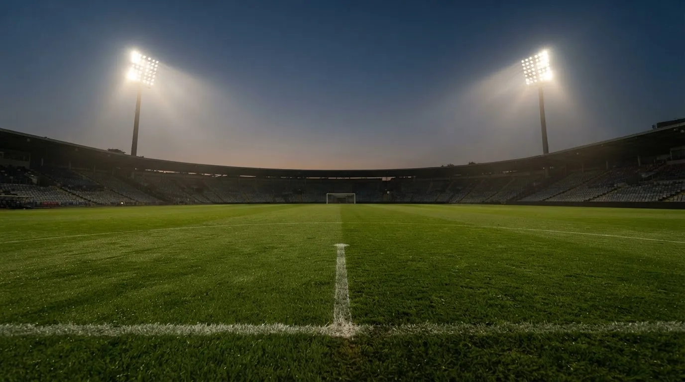 An empty football stadium with floodlight masts at dusk