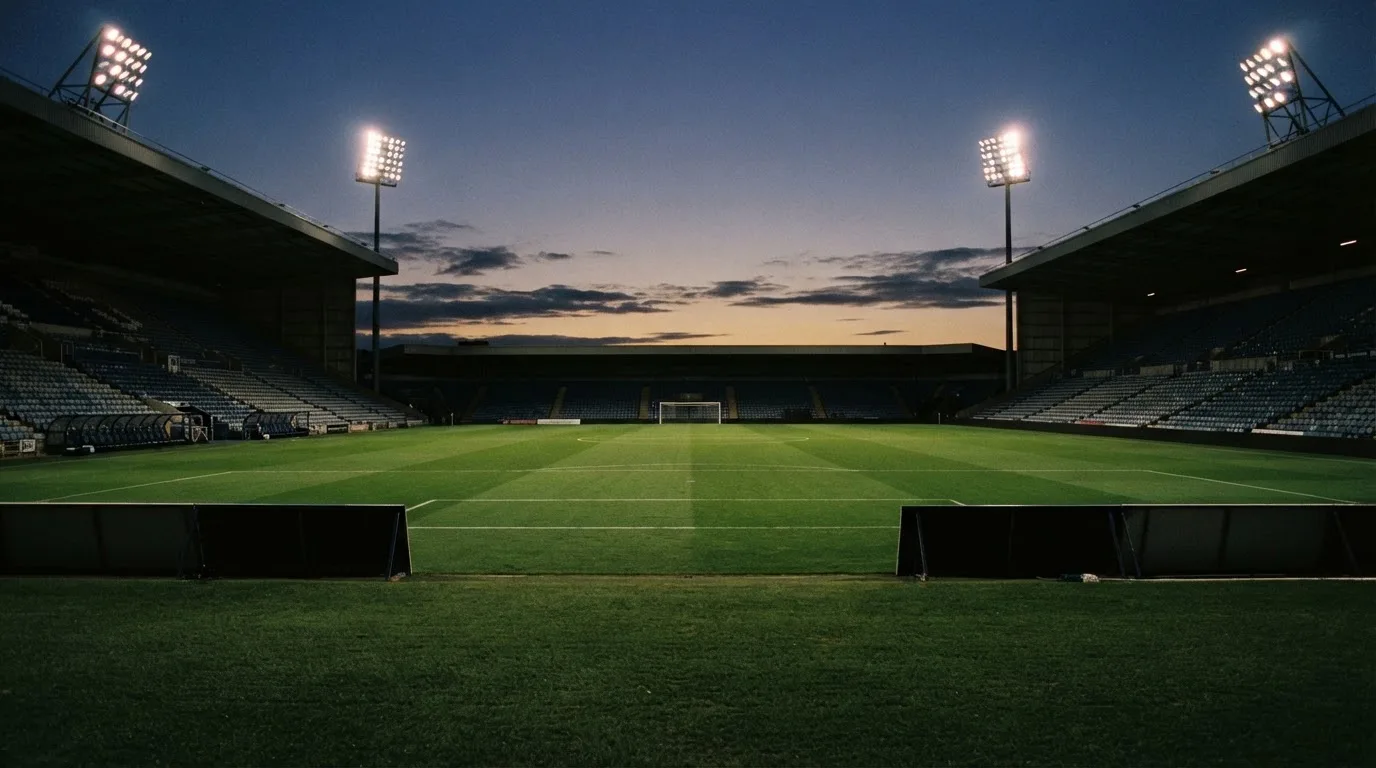 An empty football stadium with floodlight masts at dusk