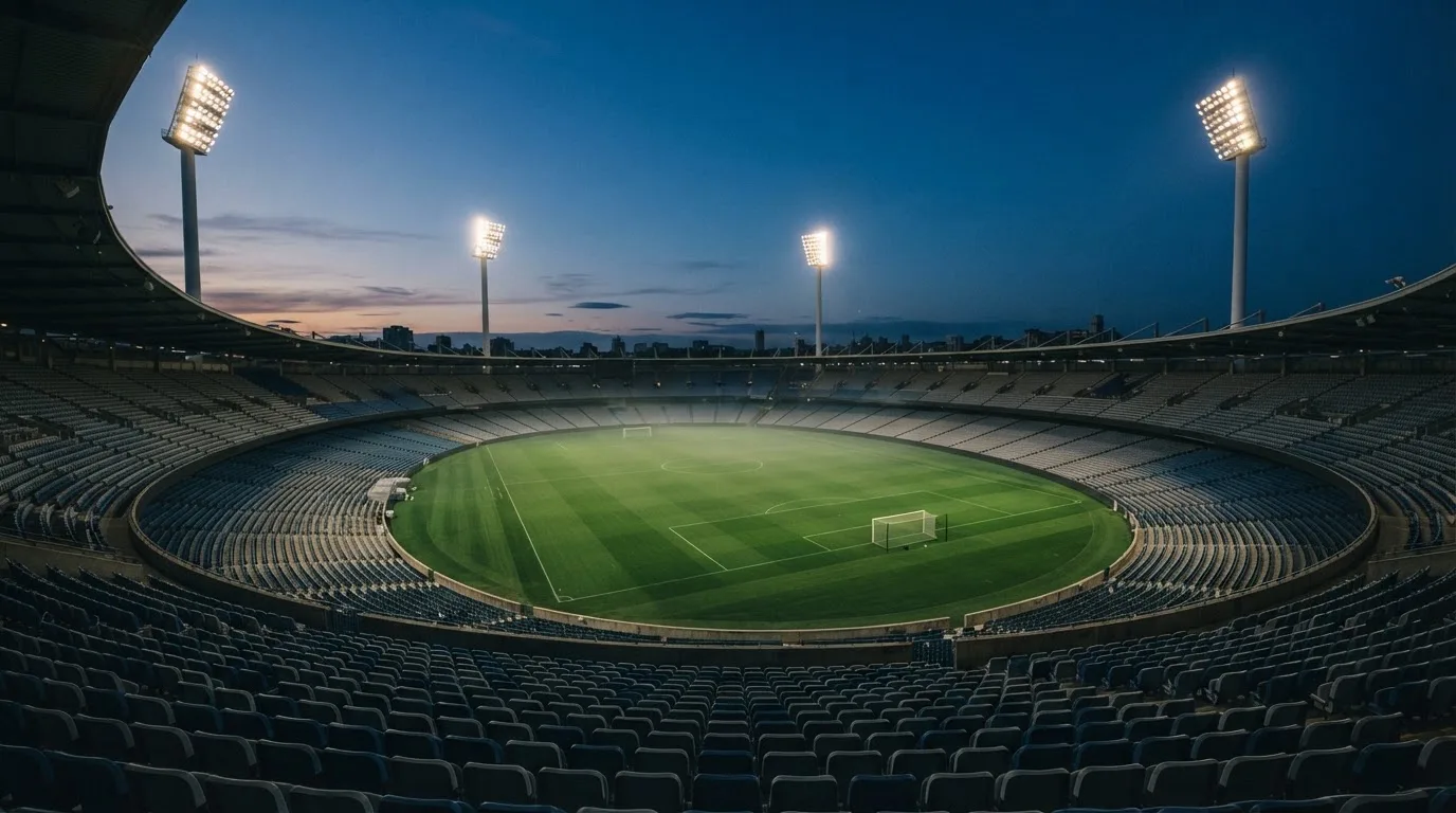 An empty football stadium with floodlight masts at dusk