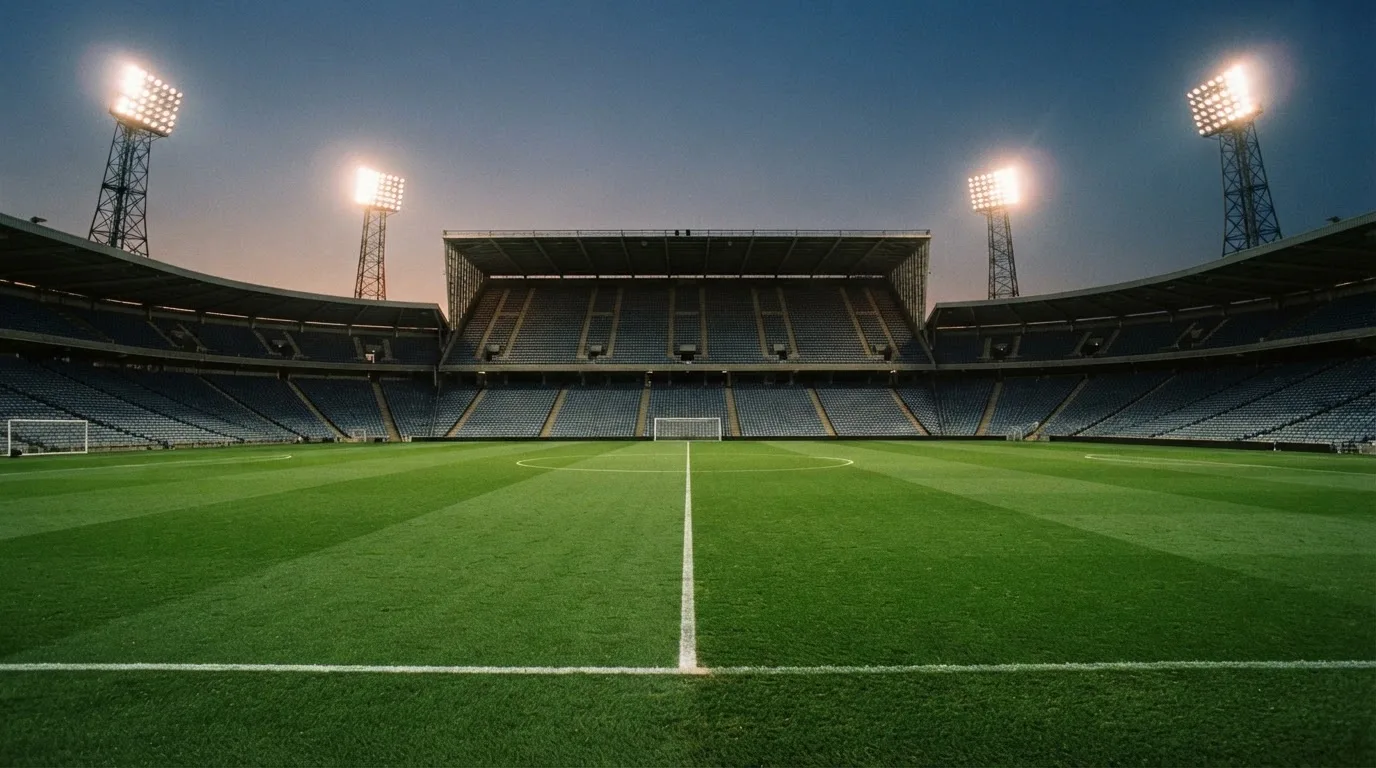 An empty football stadium with floodlight masts at dusk