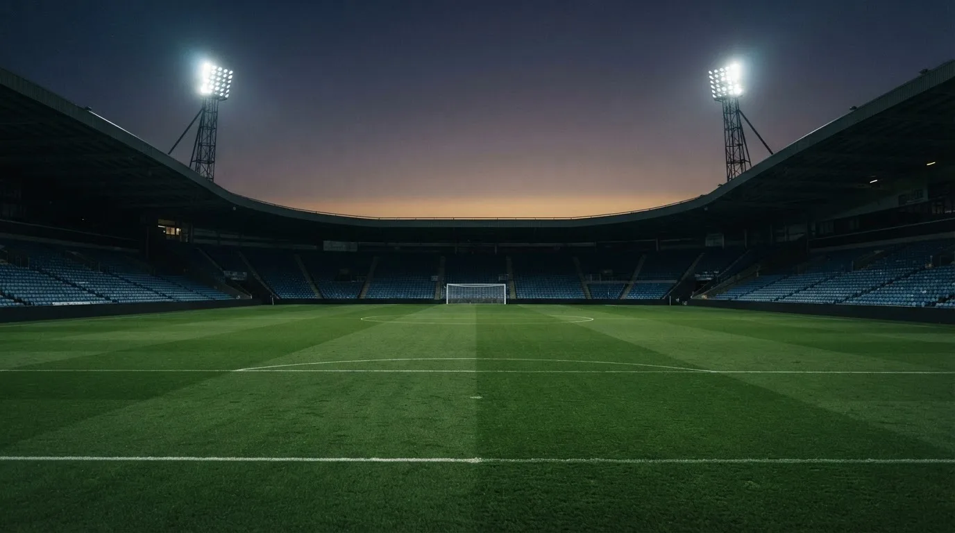 An empty football stadium with floodlight masts at dusk