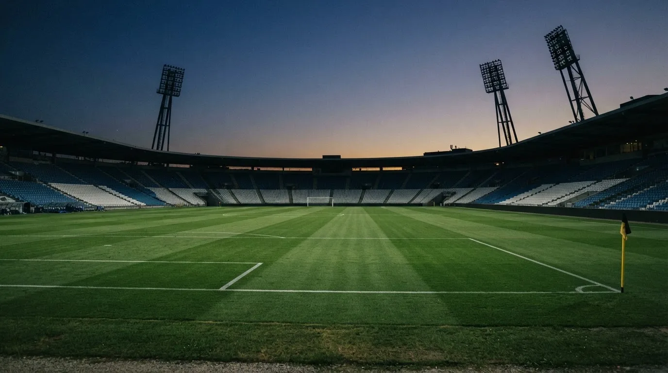 An empty football stadium with floodlight masts at dusk