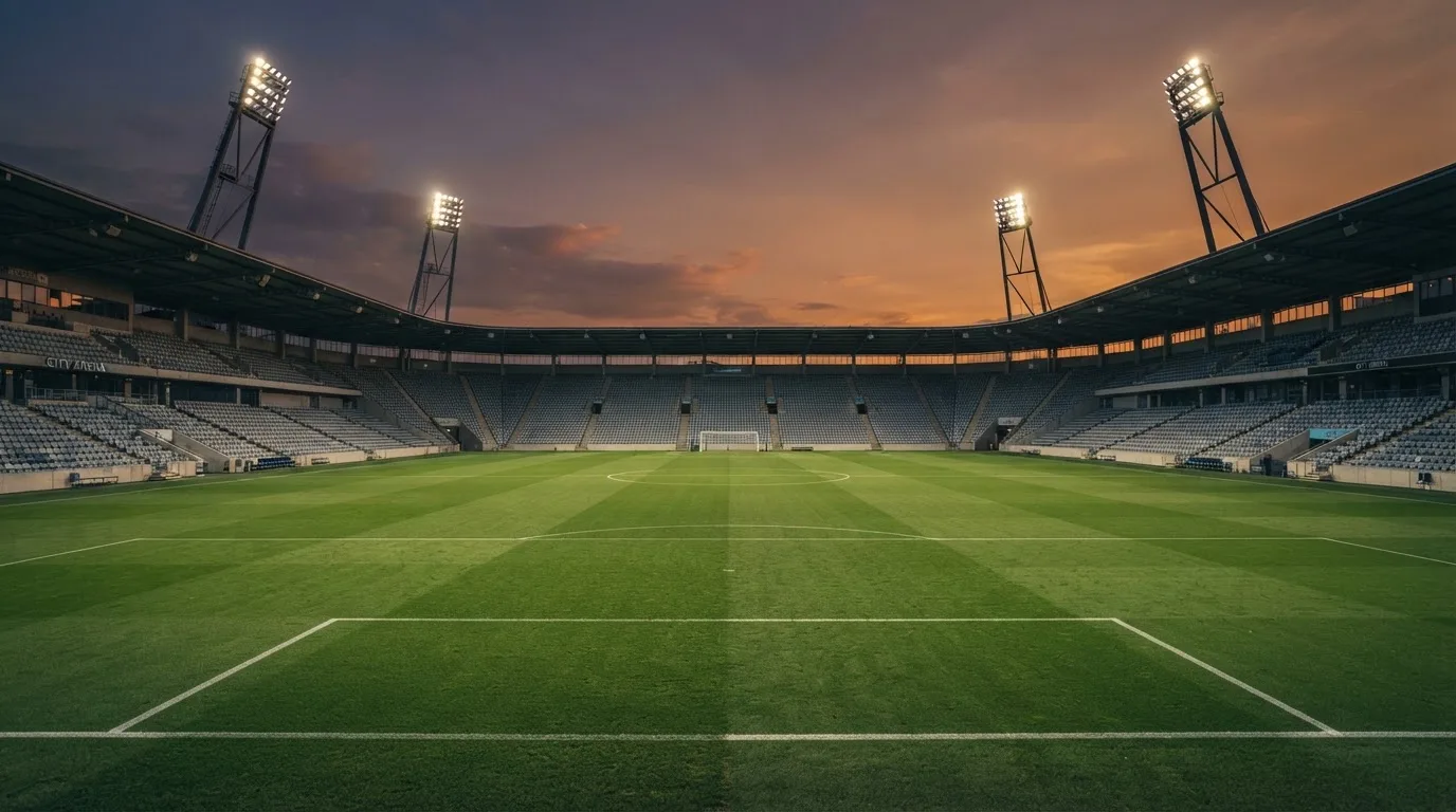 An empty football stadium with floodlight masts at dusk