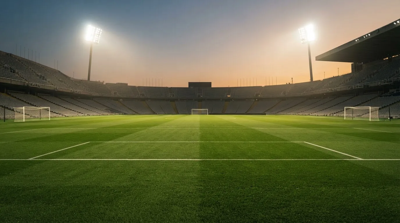An empty football stadium with floodlight masts at dusk