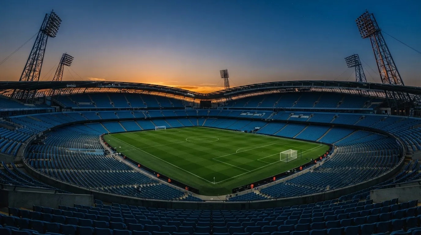 An empty football stadium with floodlight masts at dusk