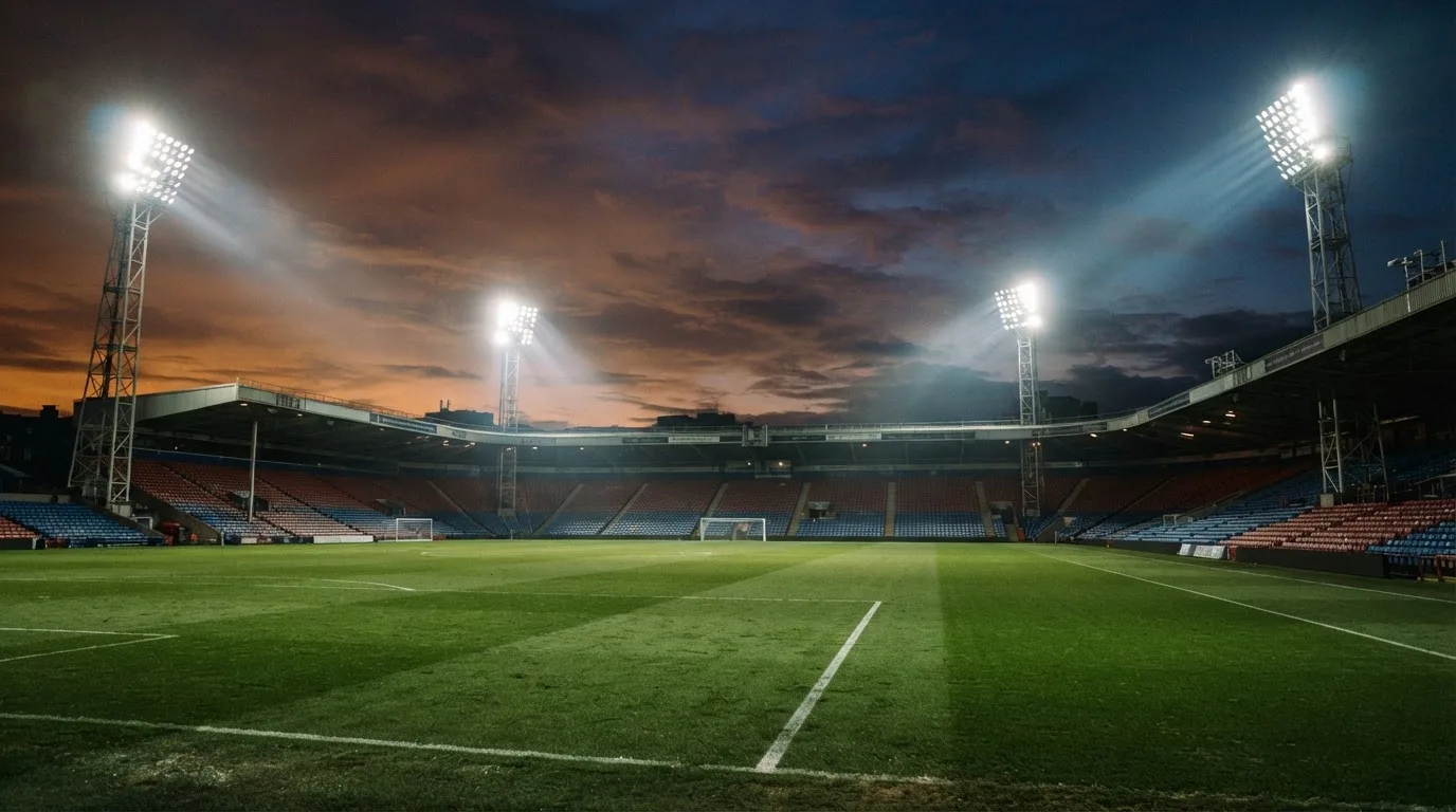 An empty football stadium with floodlight masts at dusk