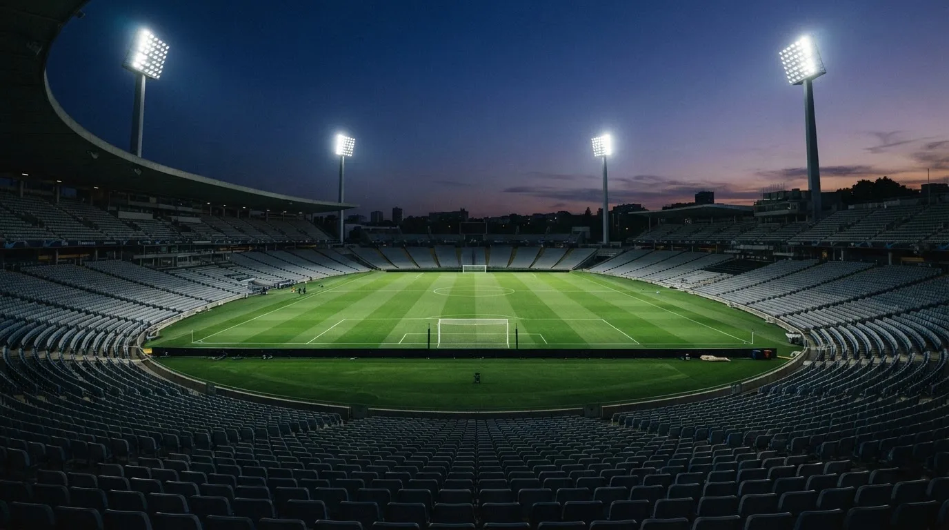 An empty football stadium with floodlight masts at dusk