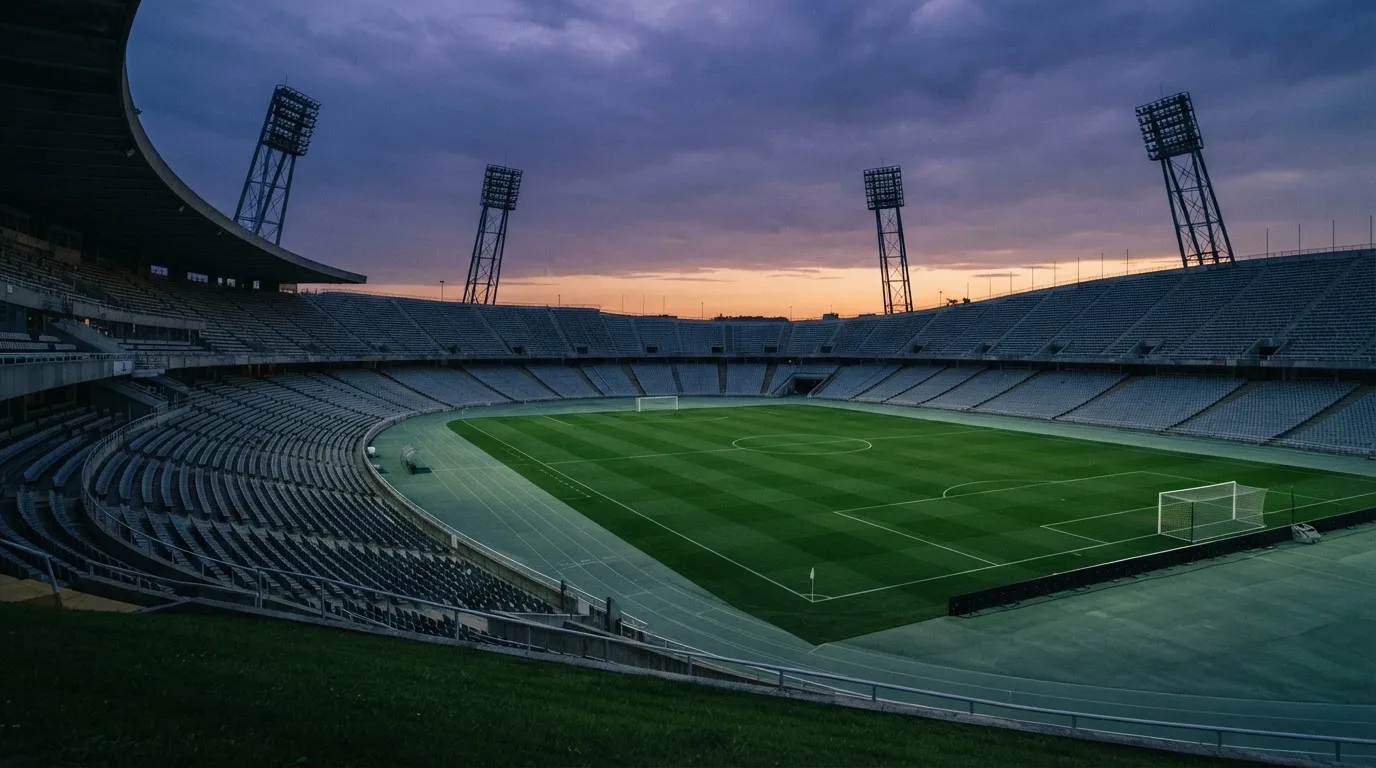 An empty football stadium with floodlight masts at dusk