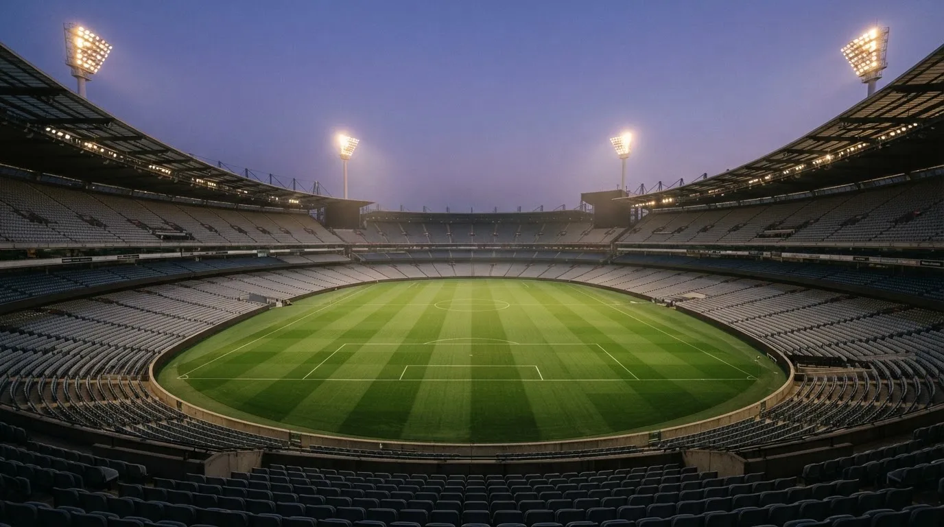 An empty football stadium with floodlight masts at dusk