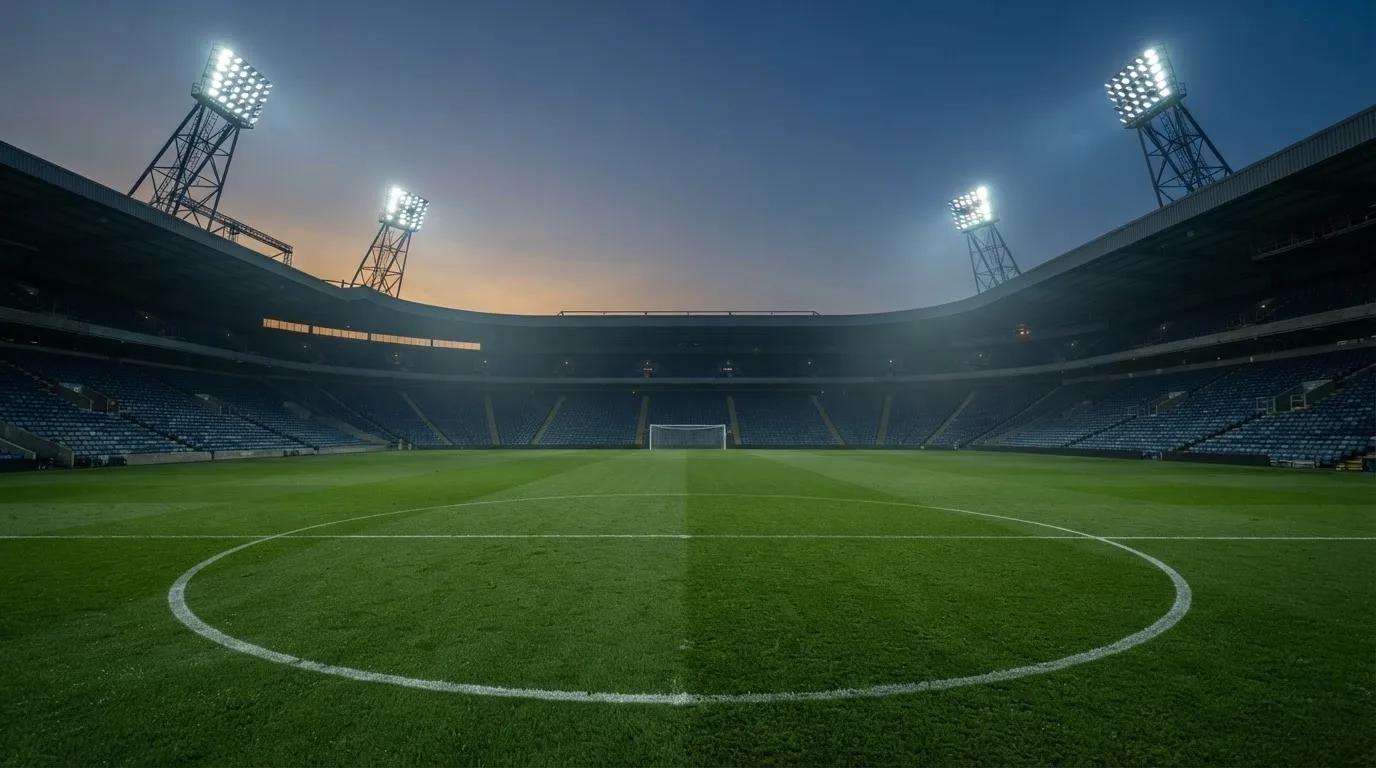 An empty football stadium with floodlight masts at dusk