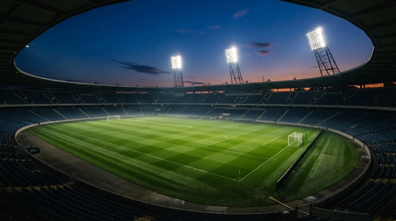 An empty football stadium with floodlight masts at dusk