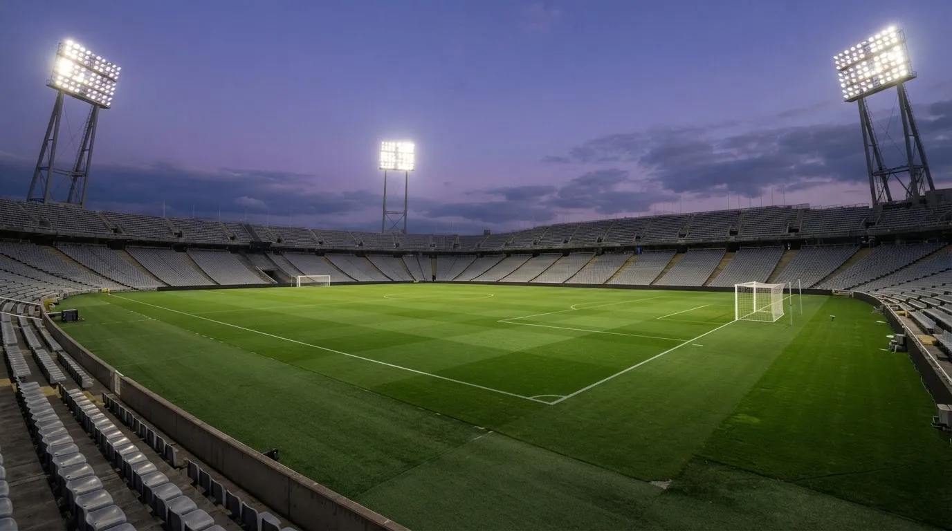 An empty football stadium with floodlight masts at dusk