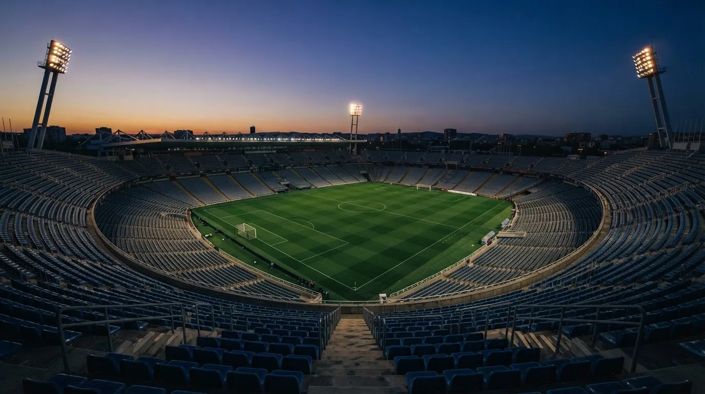 An empty football stadium with floodlight masts at dusk