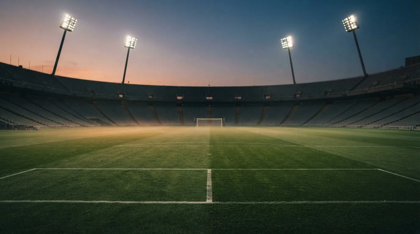 An empty football stadium with floodlight masts at dusk