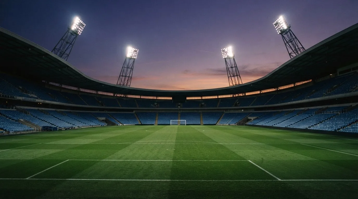 An empty football stadium with floodlight masts at dusk