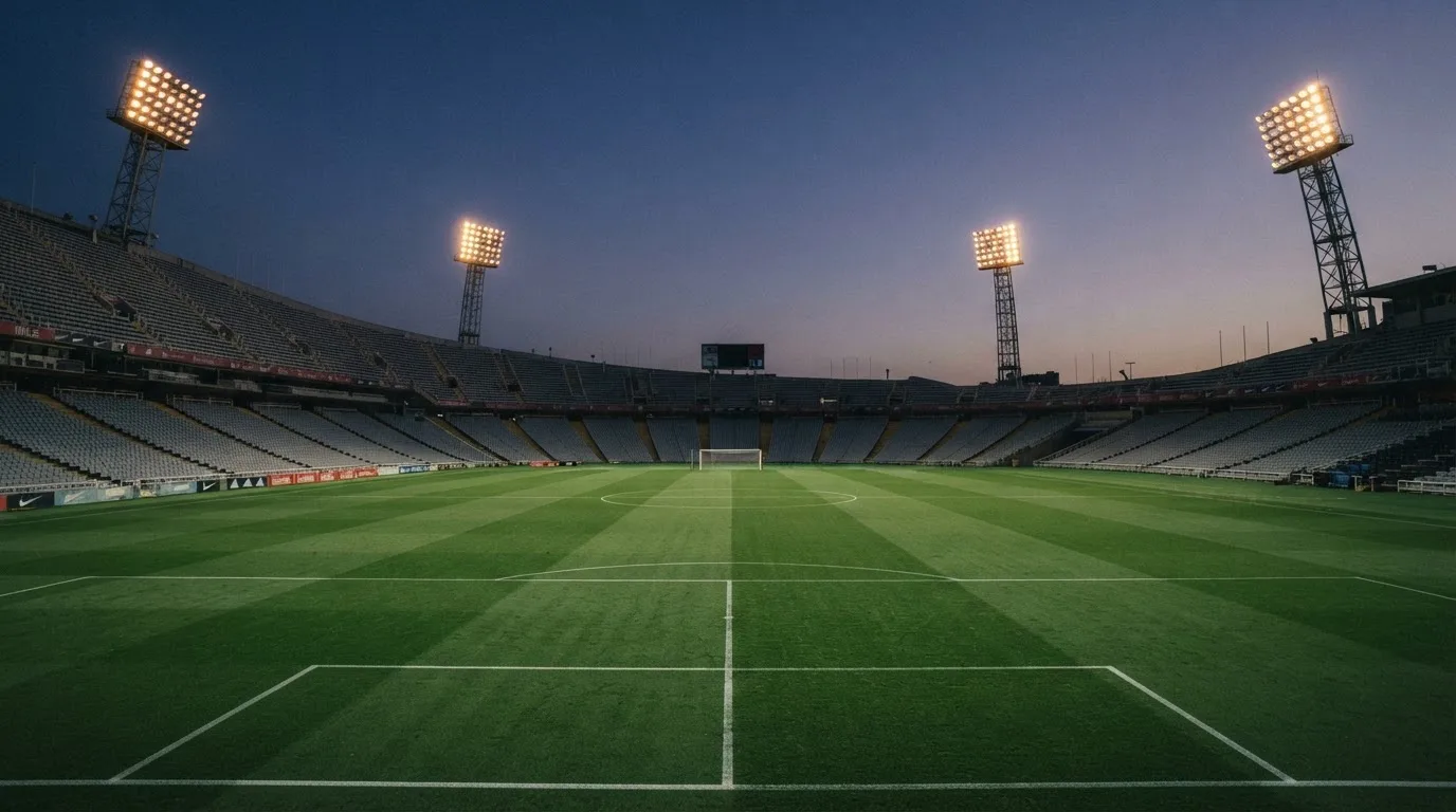 An empty football stadium with floodlight masts at dusk