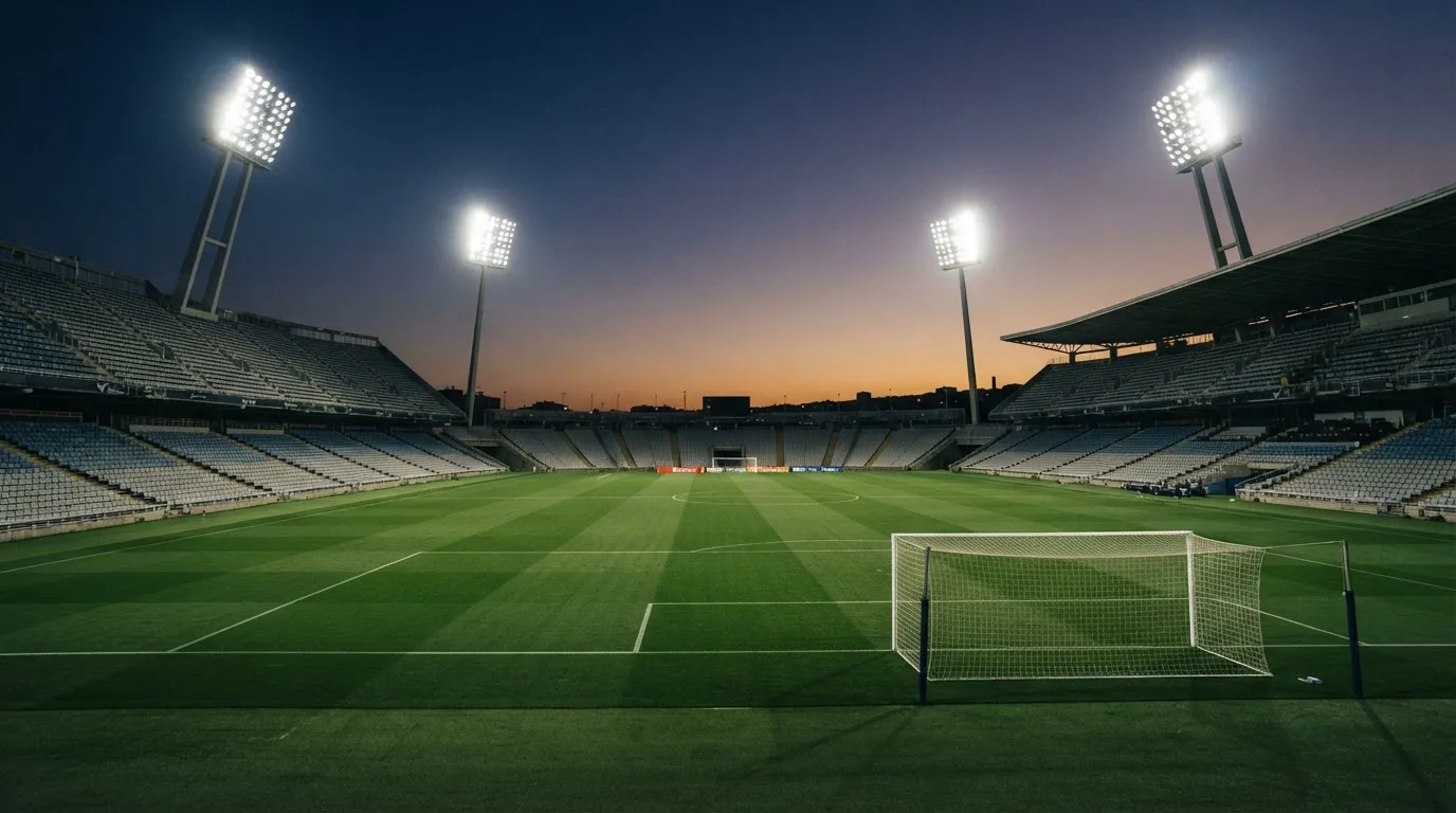 An empty football stadium with floodlight masts at dusk