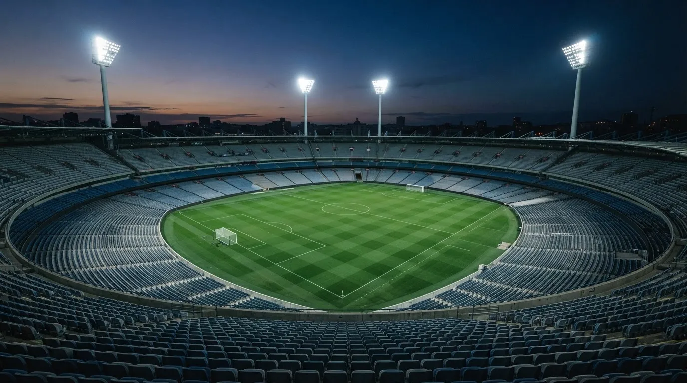 An empty football stadium with floodlight masts at dusk