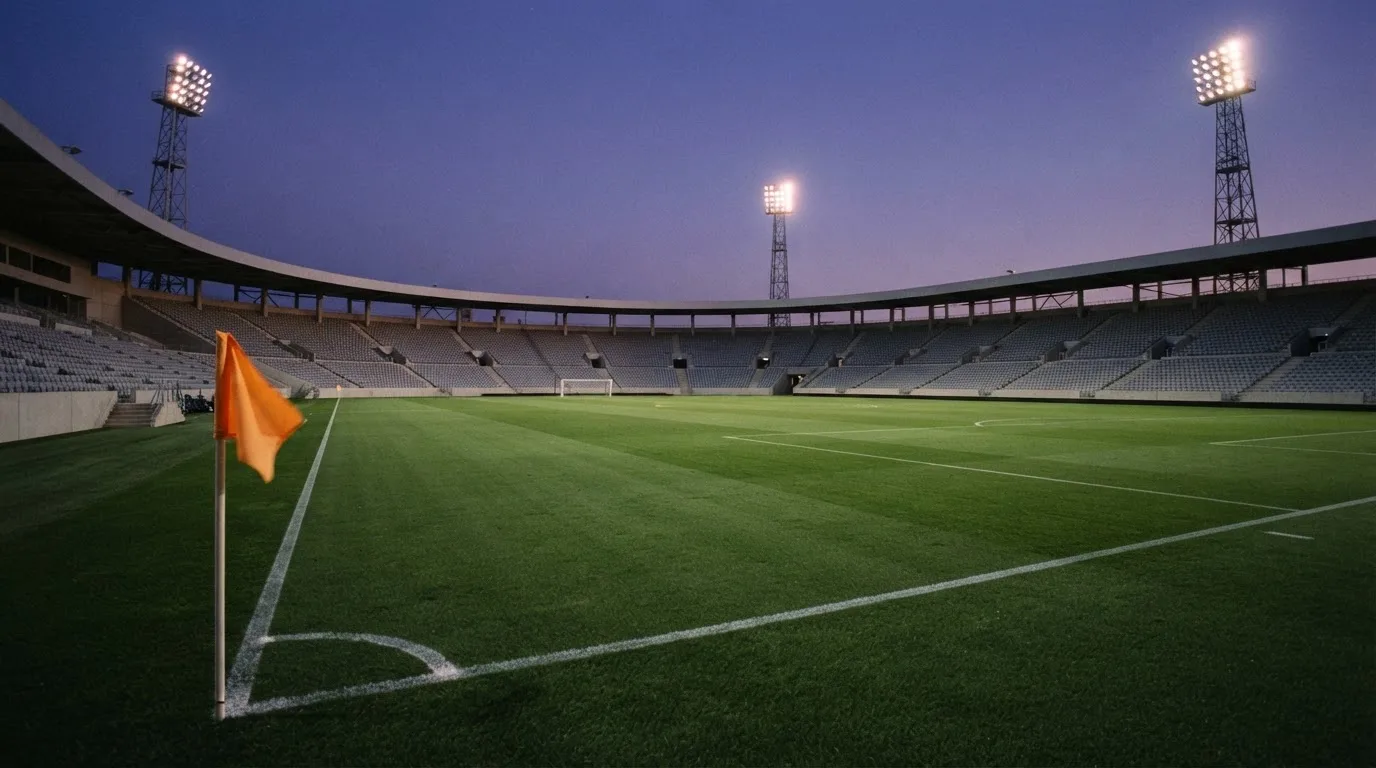 An empty football stadium with floodlight masts at dusk