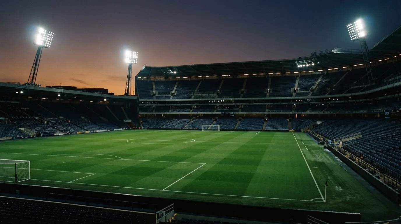 An empty football stadium with floodlight masts at dusk
