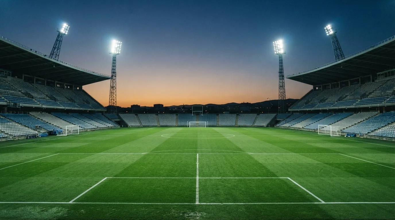 An empty football stadium with floodlight masts at dusk