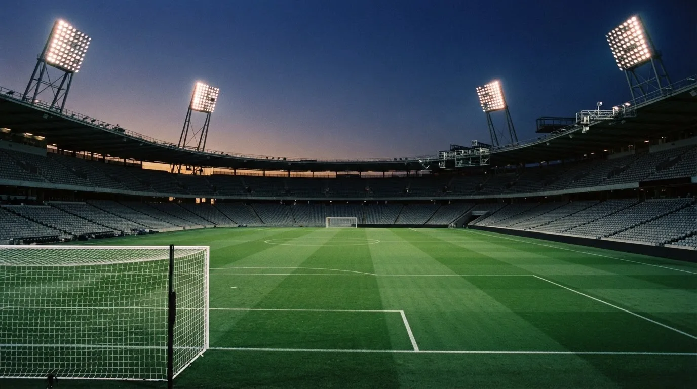 An empty football stadium with floodlight masts at dusk