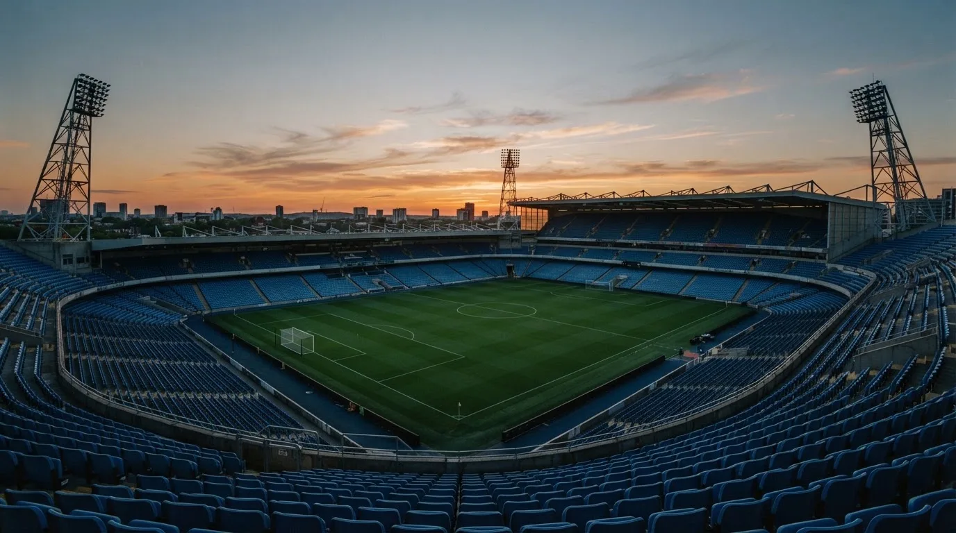 An empty football stadium with floodlight masts at dusk
