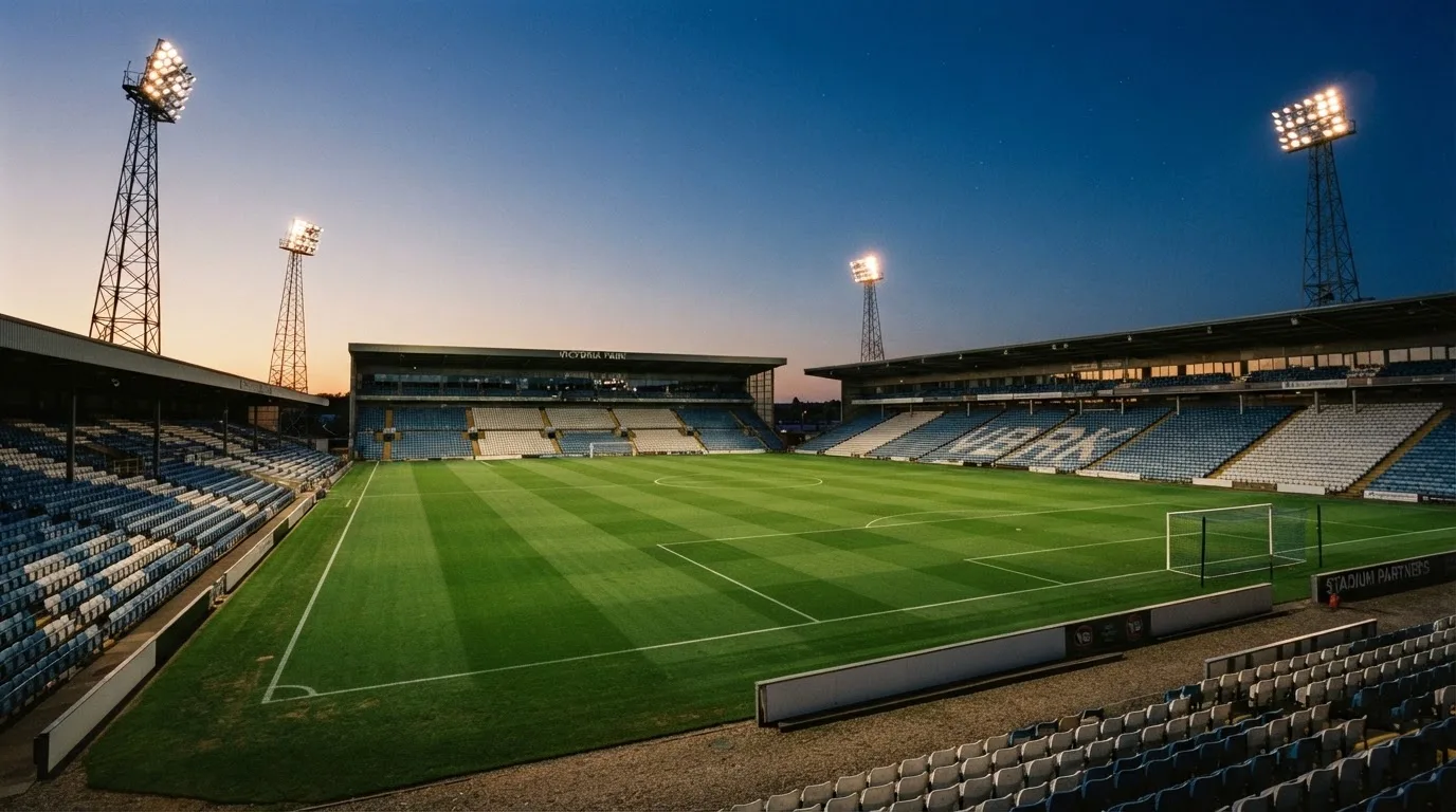 An empty football stadium with floodlight masts at dusk