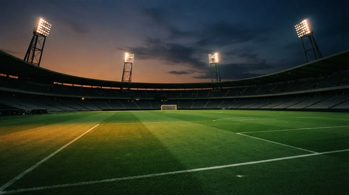 An empty football stadium with floodlight masts at dusk