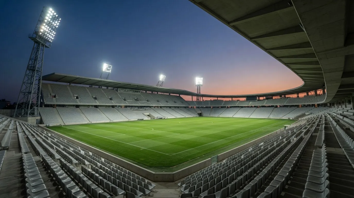 An empty football stadium with floodlight masts at dusk