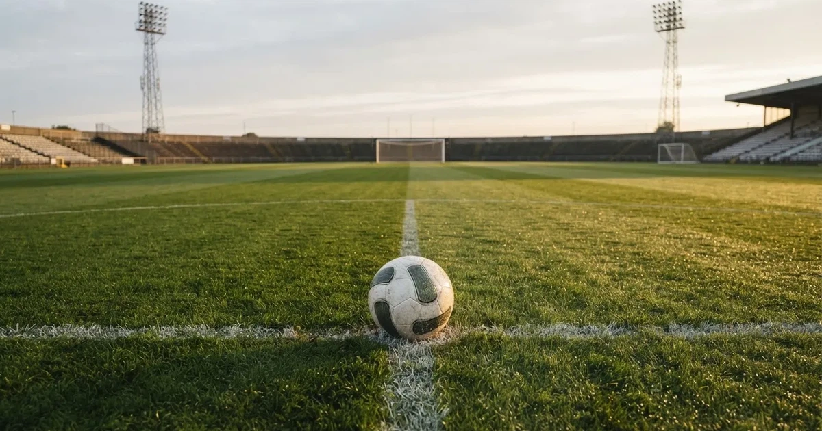 A ball on the centre spot of a grass pitch in morning light