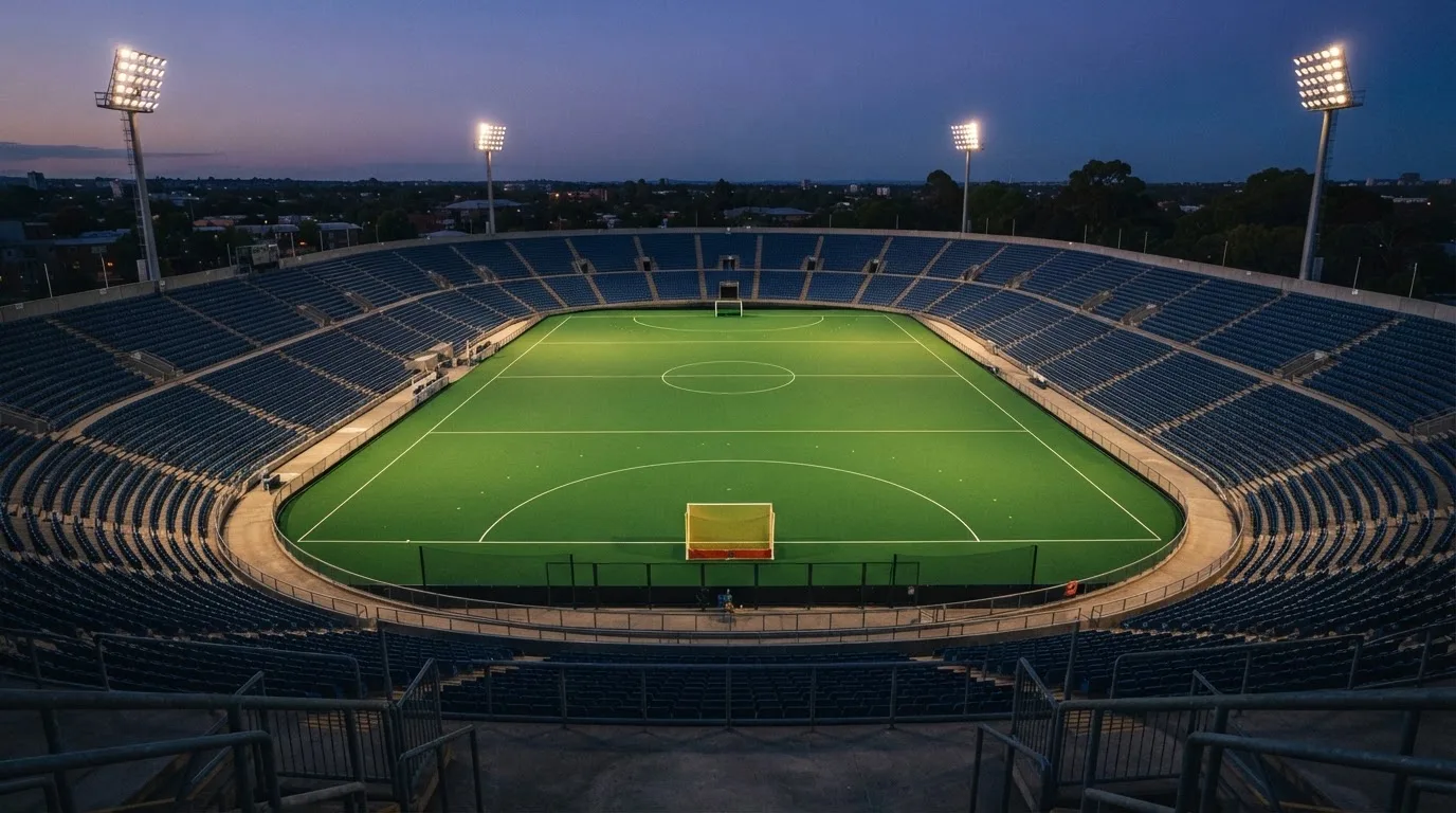 An empty football stadium with floodlight masts at dusk