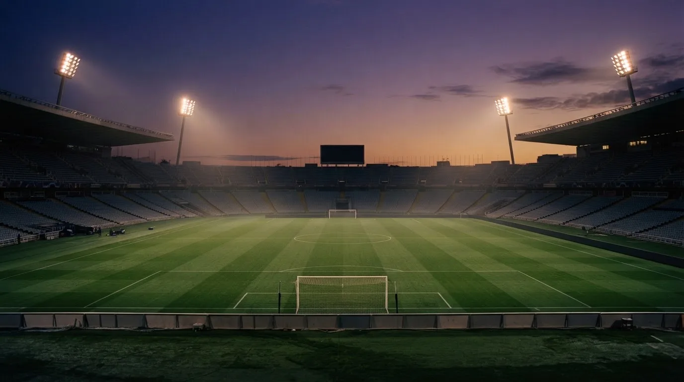 An empty football stadium with floodlight masts at dusk