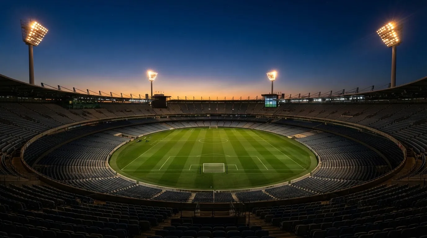 An empty football stadium with floodlight masts at dusk
