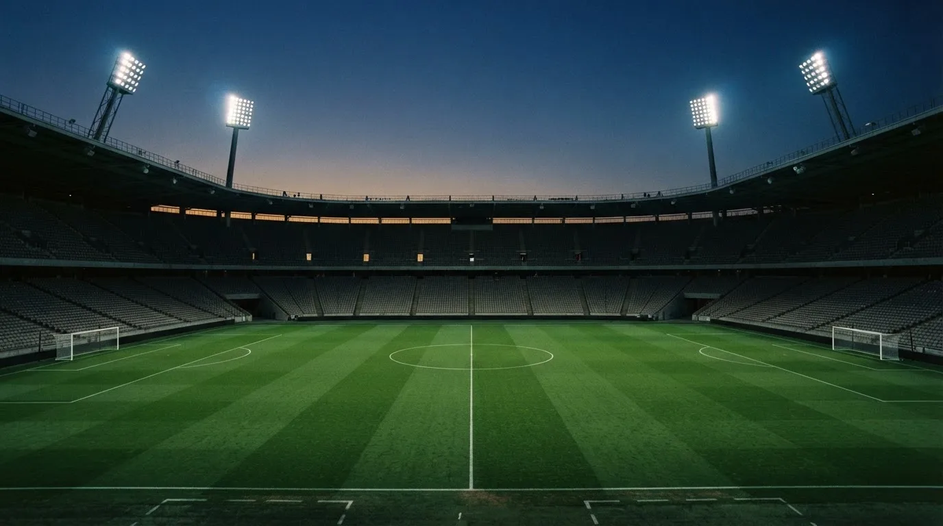 An empty football stadium with floodlight masts at dusk