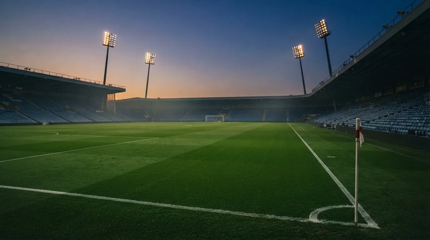 An empty football stadium with floodlight masts at dusk