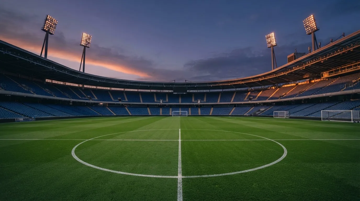 An empty football stadium with floodlight masts at dusk