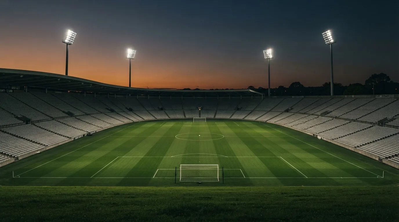 An empty football stadium with floodlight masts at dusk