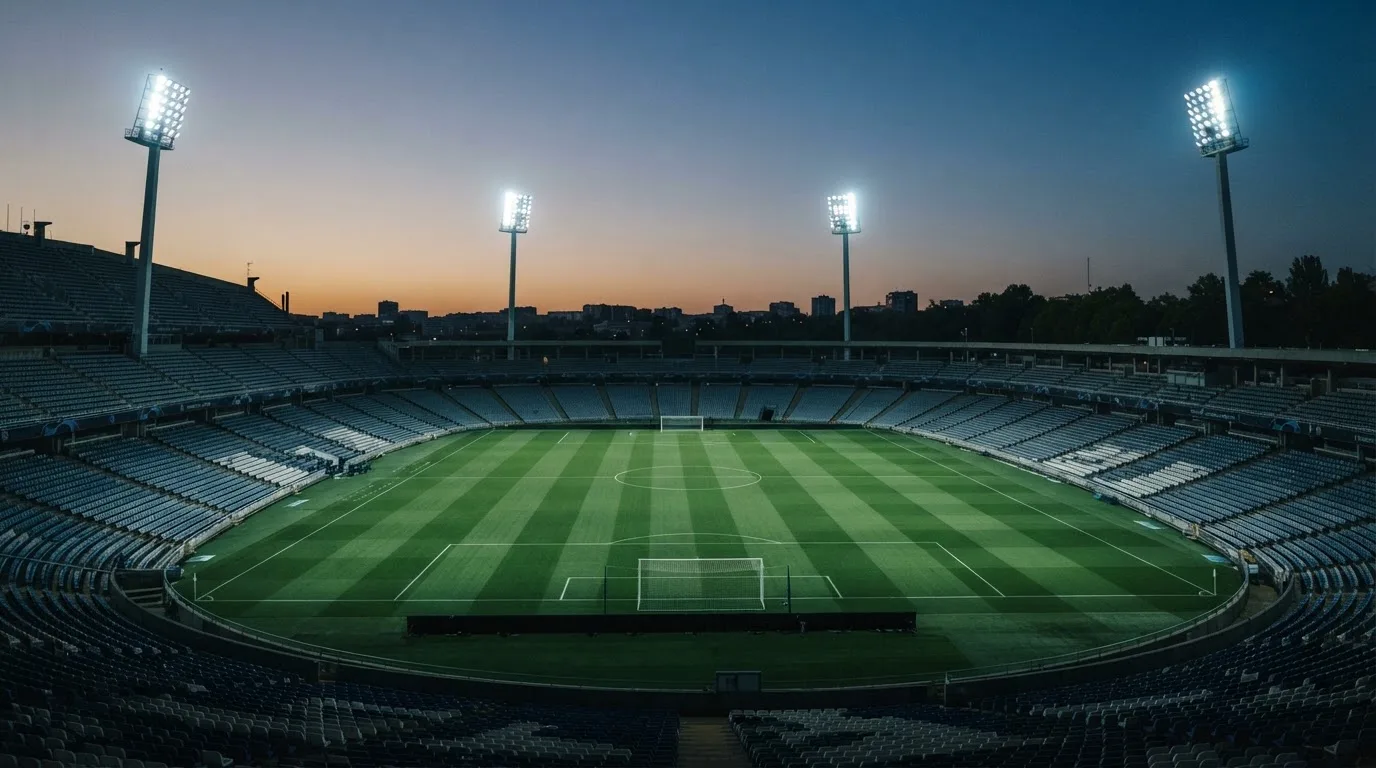 An empty football stadium with floodlight masts at dusk