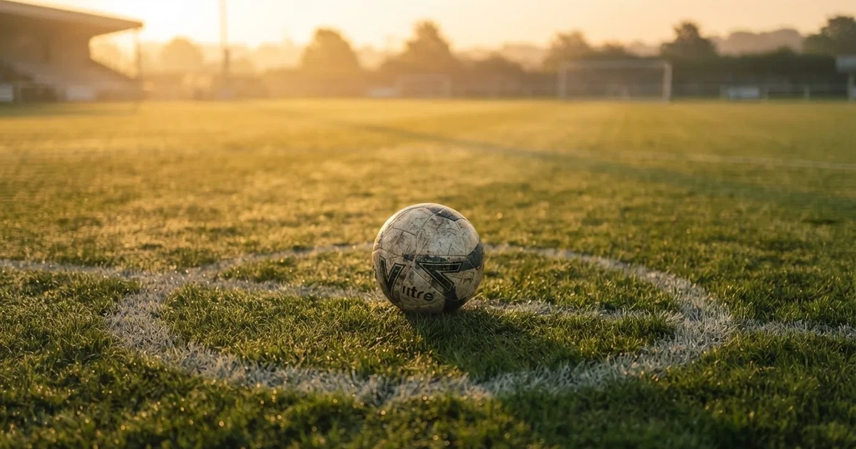 A ball on the centre spot of a grass pitch in morning light
