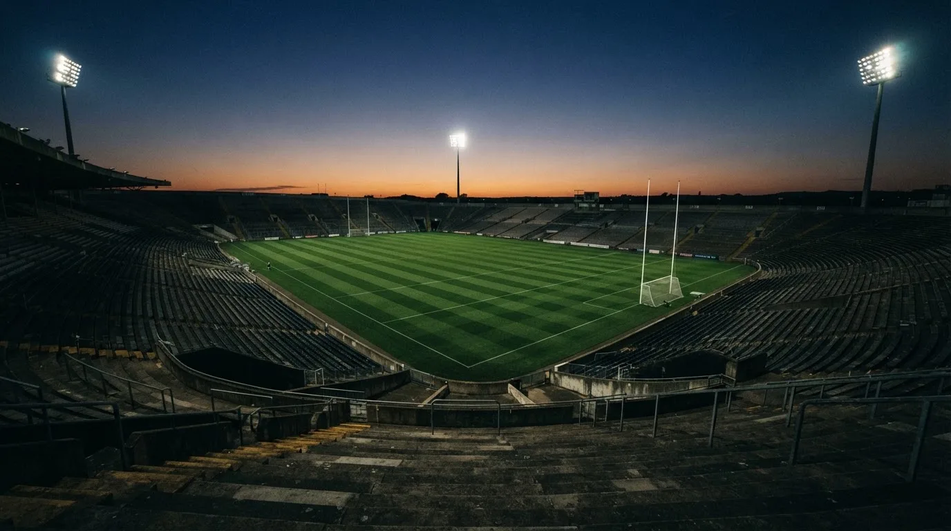 An empty football stadium with floodlight masts at dusk