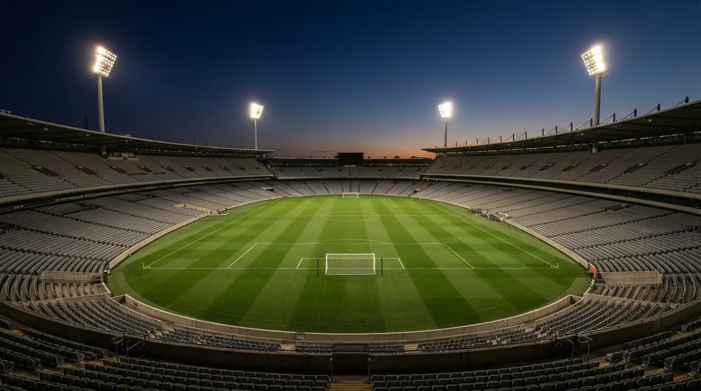 An empty football stadium with floodlight masts at dusk