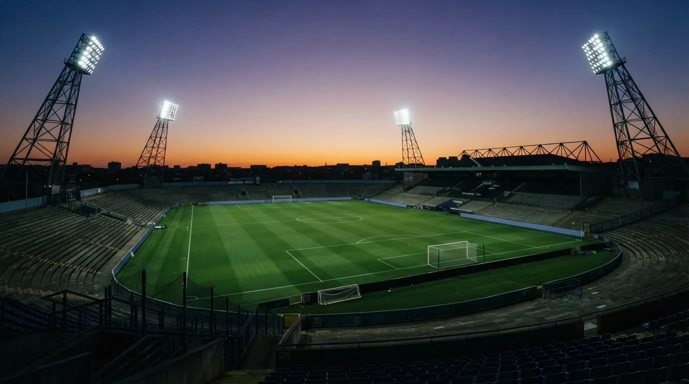 An empty football stadium with floodlight masts at dusk
