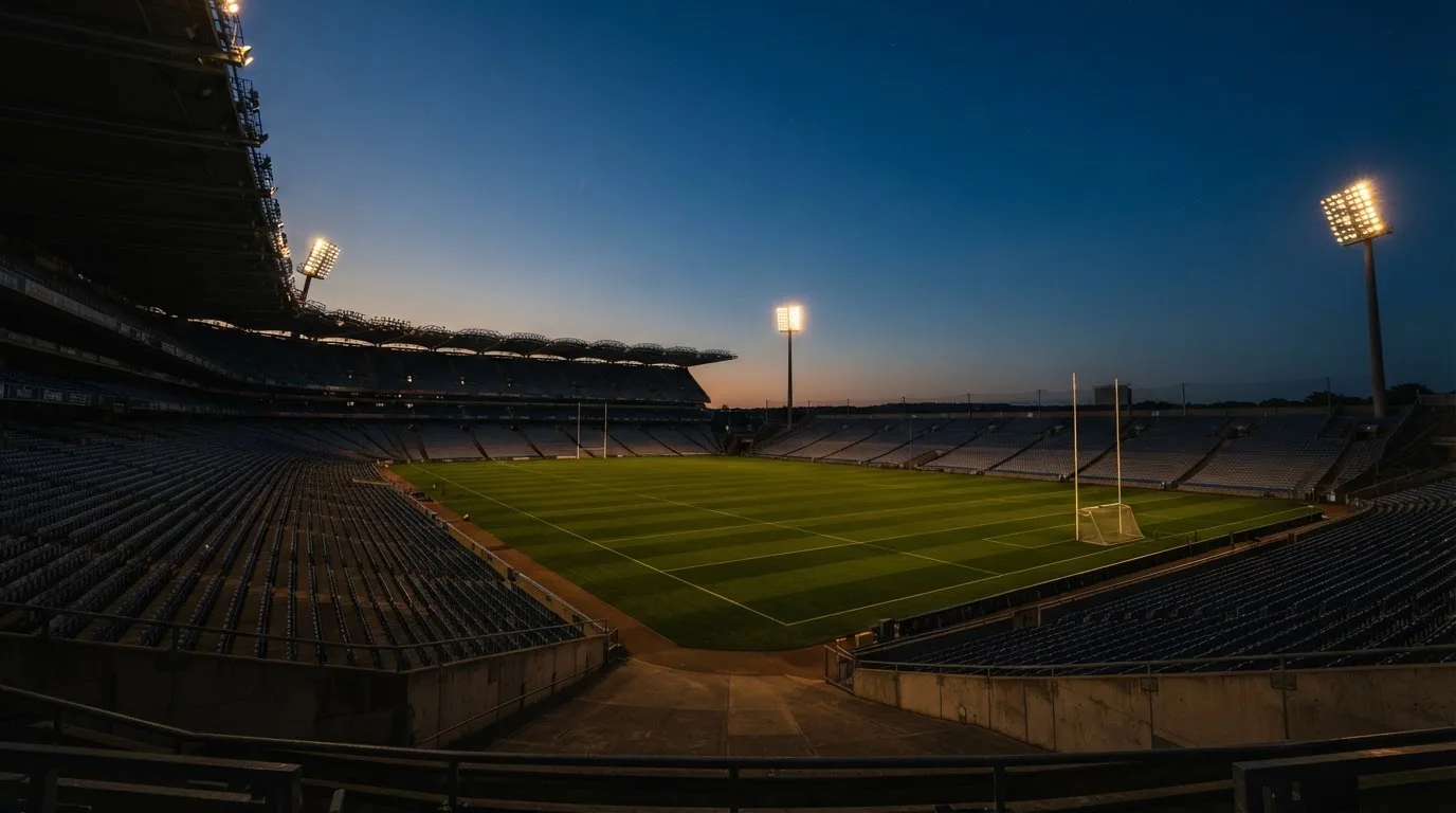 An empty football stadium with floodlight masts at dusk