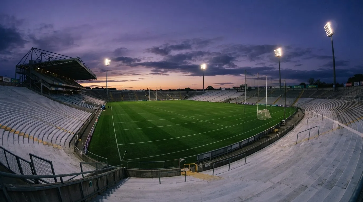 An empty football stadium with floodlight masts at dusk