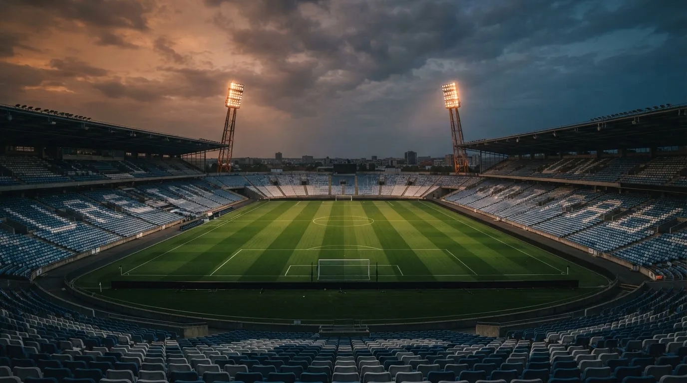 An empty football stadium with floodlight masts at dusk