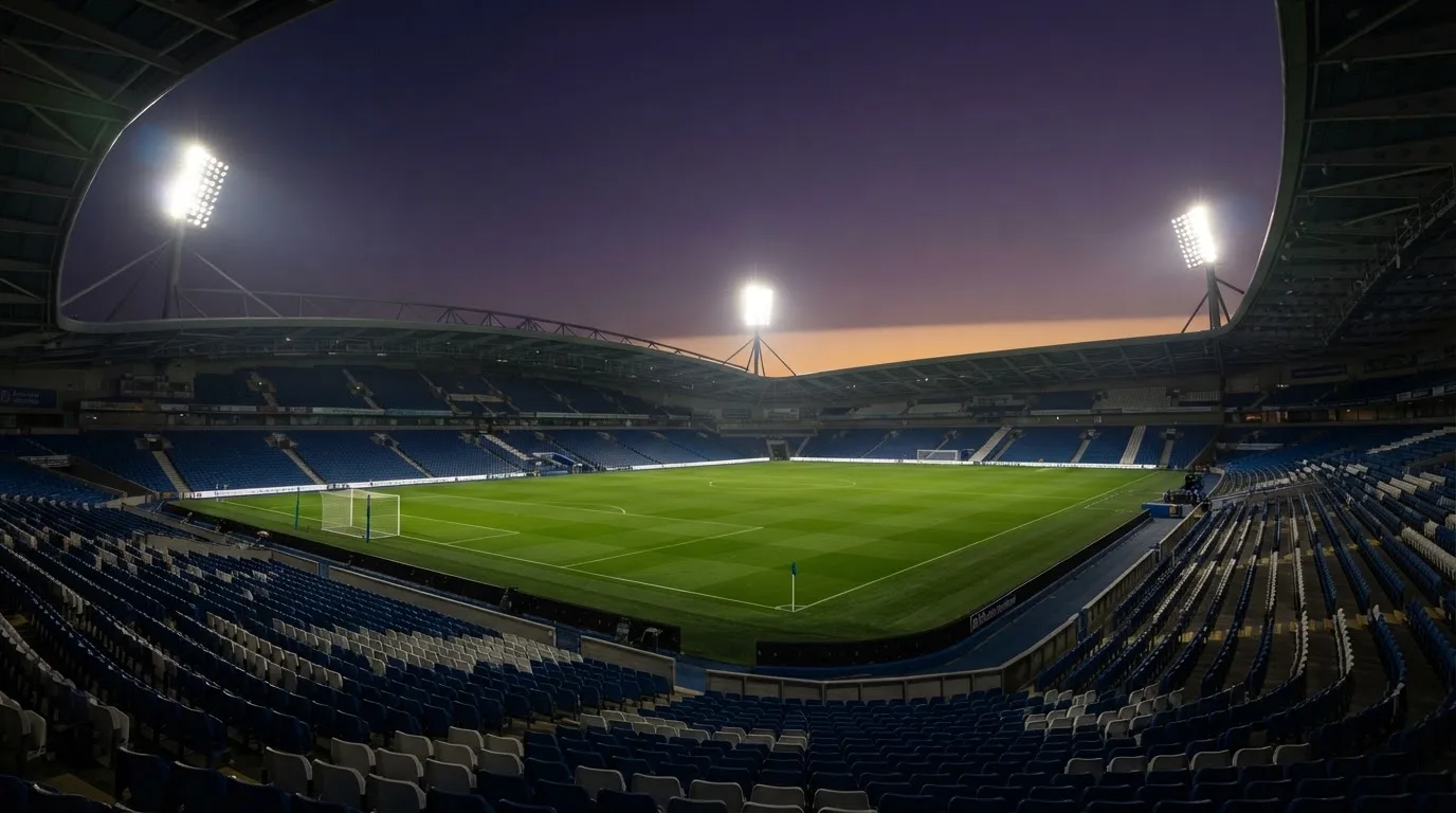 An empty football stadium with floodlight masts at dusk
