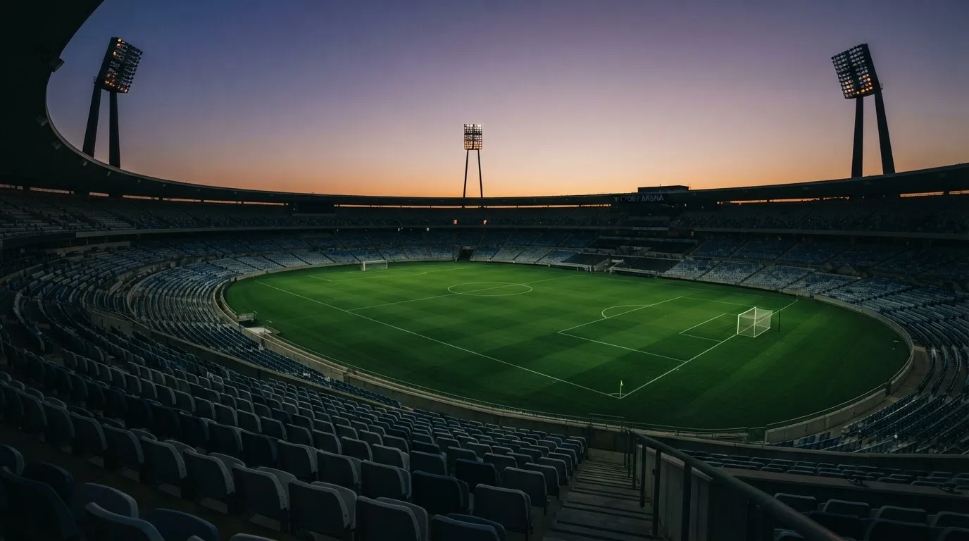 An empty football stadium with floodlight masts at dusk
