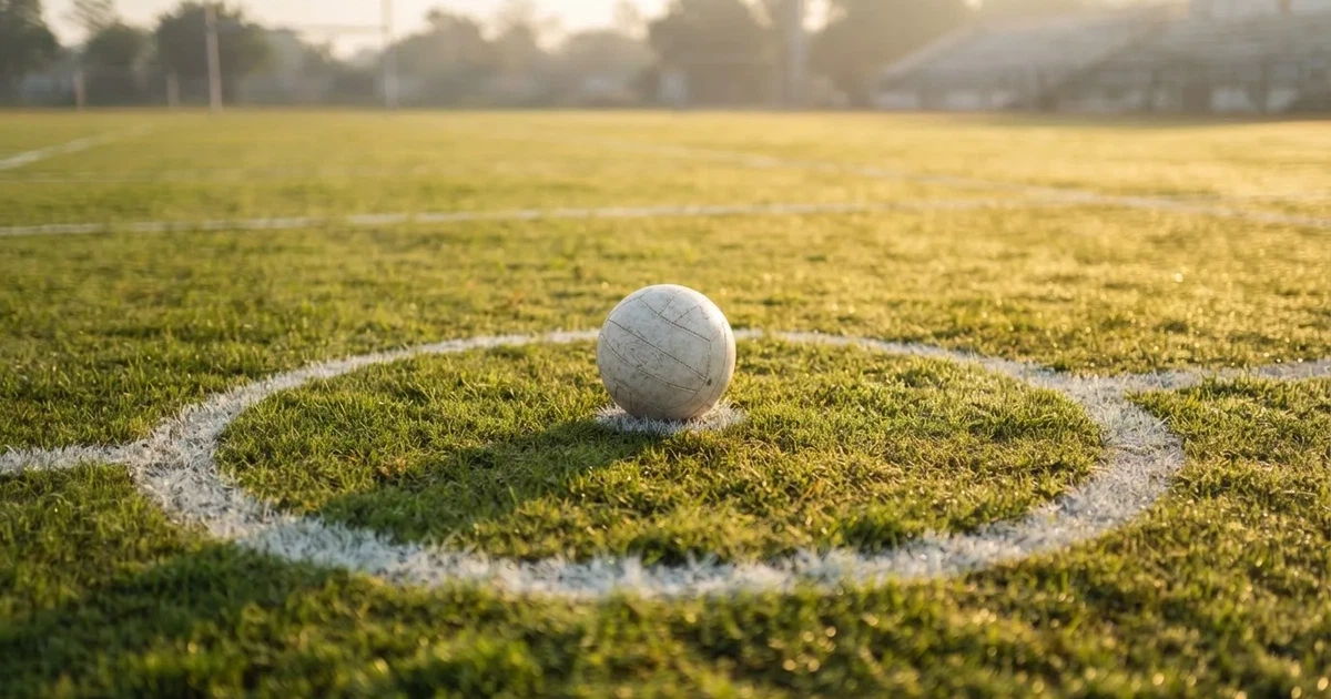 A ball on the centre spot of a grass pitch in morning light